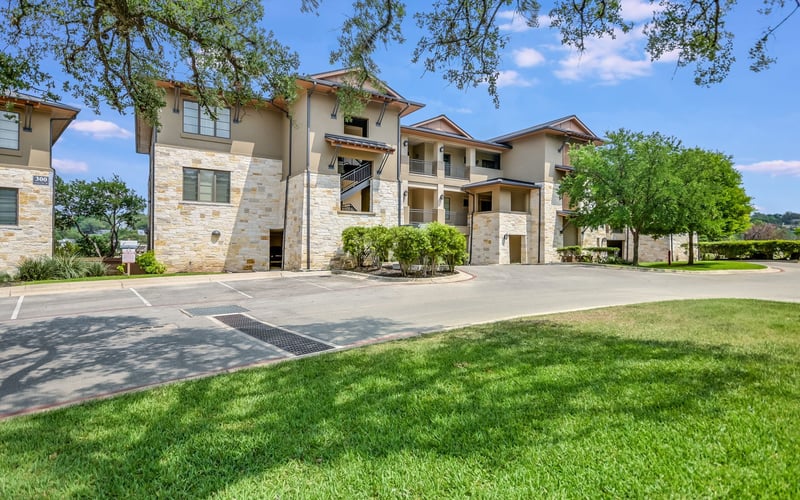 Beautiful luxury house in Texas with a spacious driveway, surrounded by lush landscaping and mature trees